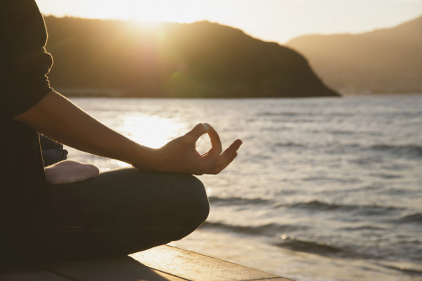woman meditating beach at sunset